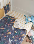 Lifestyle view of Our Planet coverlet on cot, reversible quilted cotton with ocean prints creating a fun, cosy, design-led sleep space