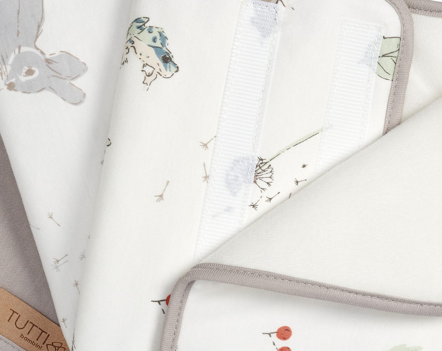Close-up of Cocoon cot wraps showing soft padded cotton fabric with neutral woodland print and secure Velcro fastening