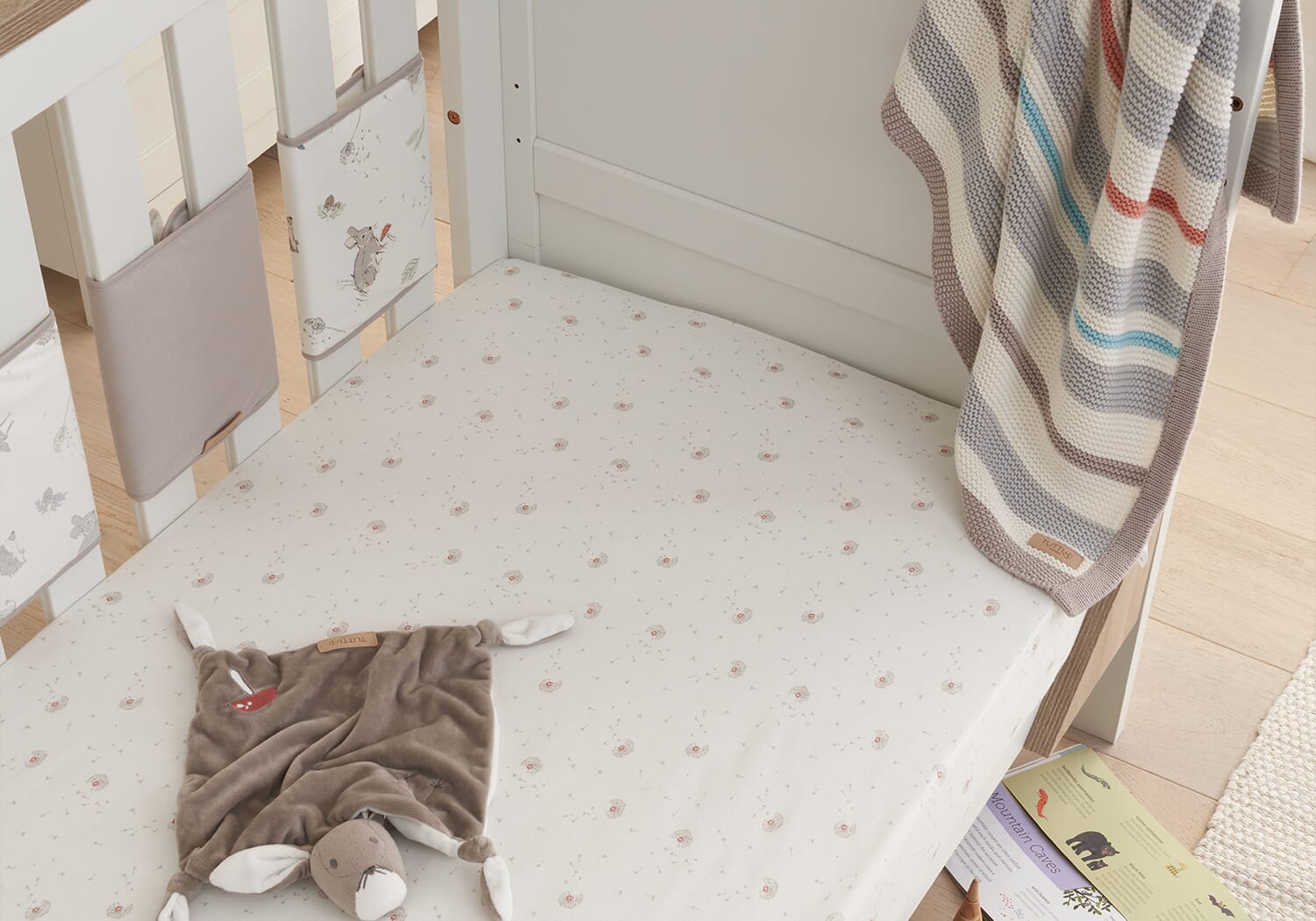 Cocoon cot wraps styled on a cot mattress, creating a softly padded sleep space with neutral tones and woodland details