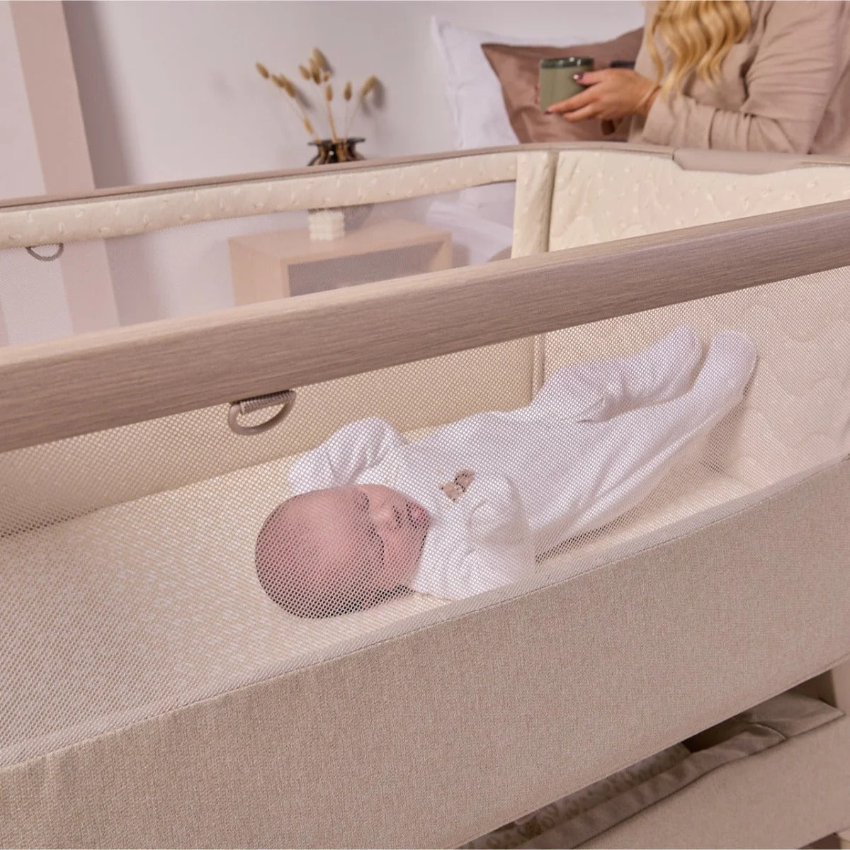 baby resting peacefully in the cozee air 2 showing mum holding mug in the background