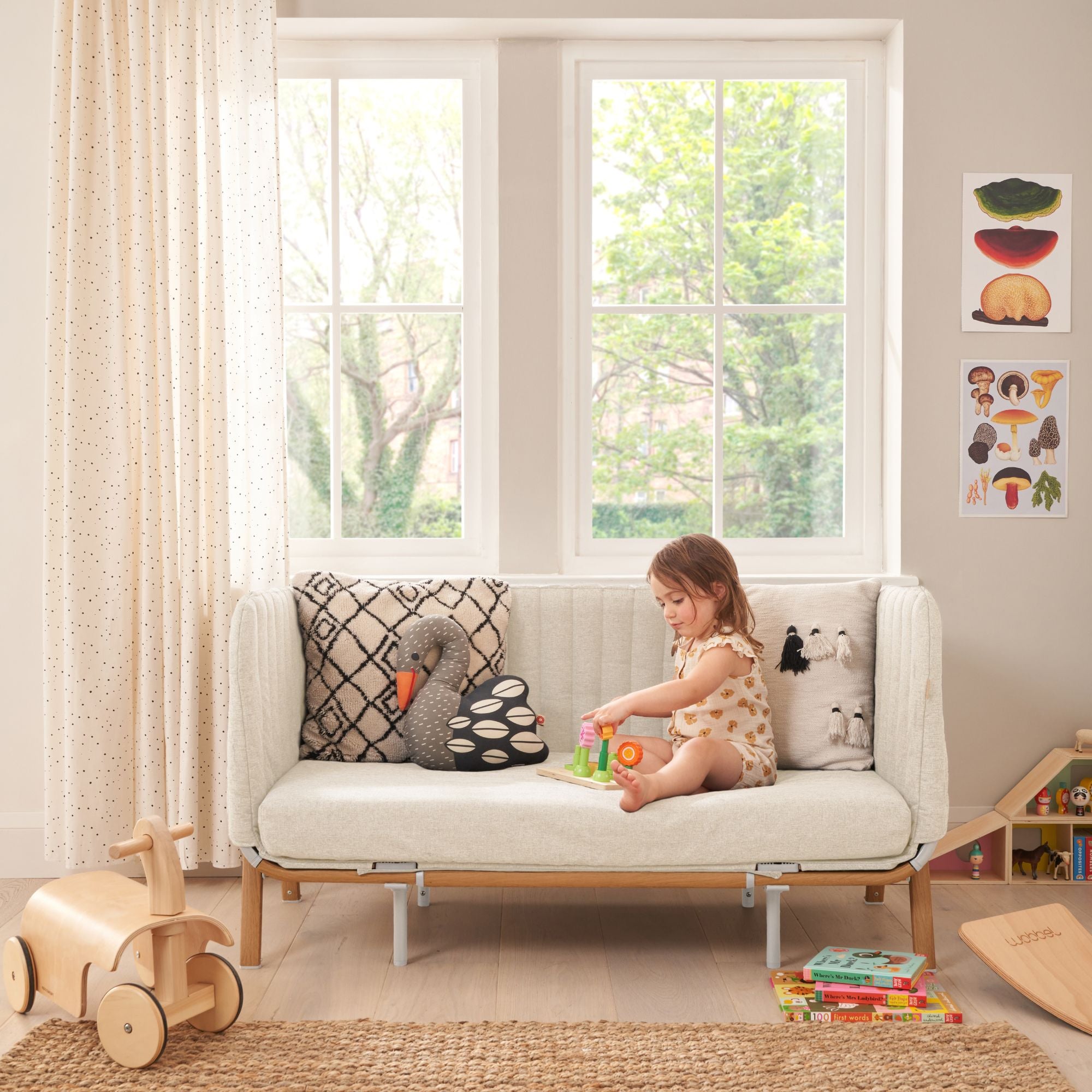 Room view of CoZee XL in sofa mode in Scandinavian walnut and ecru with toddler playing, showing cushioned seat and modern style
