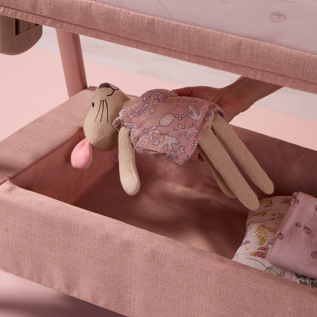 image showing a toy being placed in the spacious storage underneath the cozee zen in blush