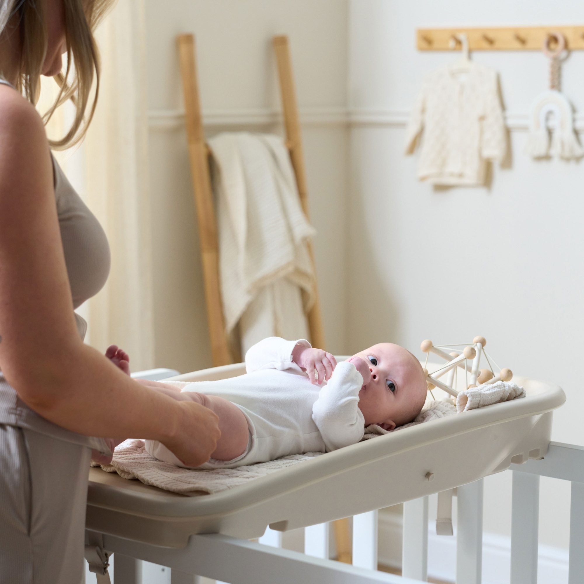 Baby lying on the Cushi Baby Changing Mat in cashmere finish, resting on a soft blanket, highlighting safe, comfortable design