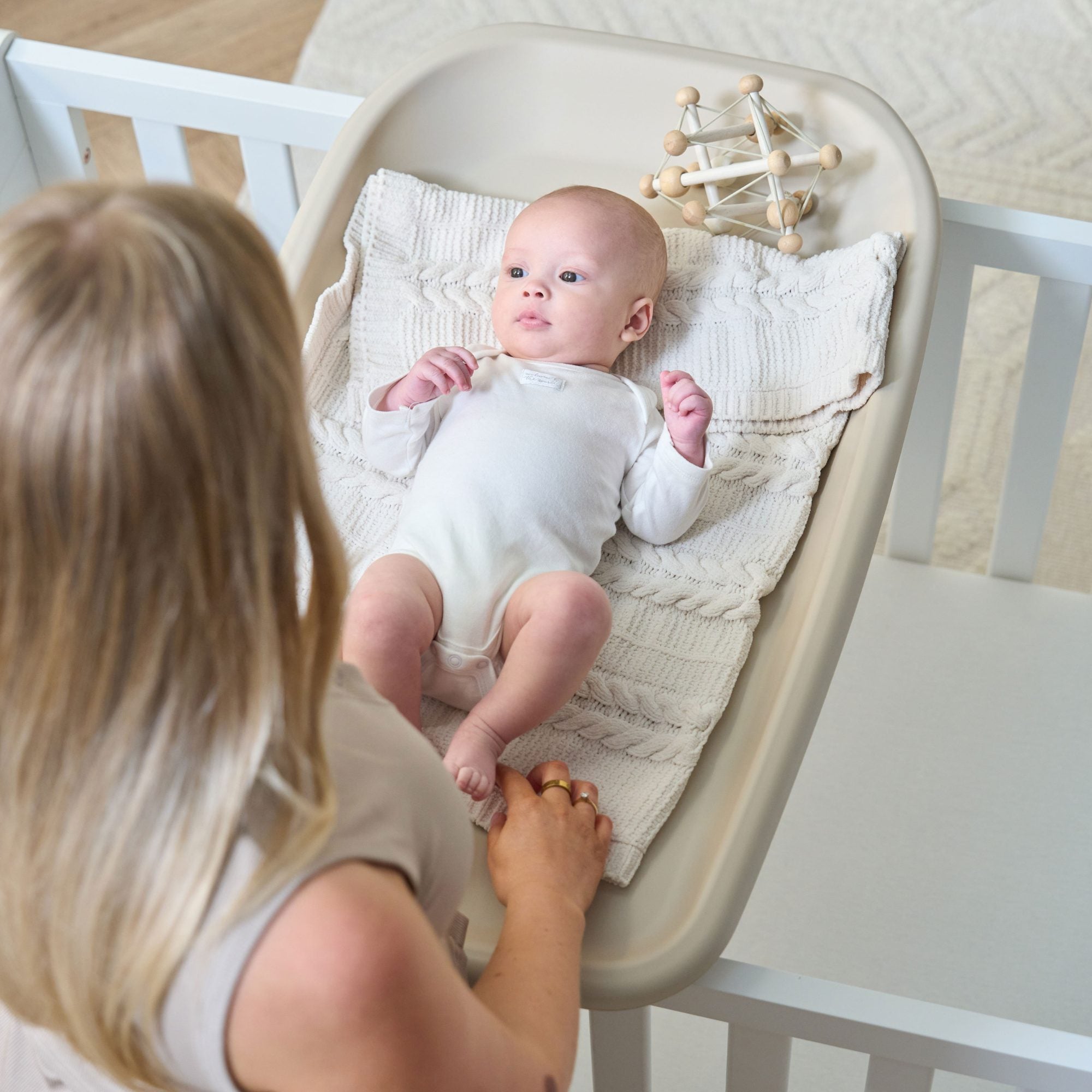 Overhead view of mum using the Cushi Baby Changing Mat in cashmere while baby lies safely during a nappy change