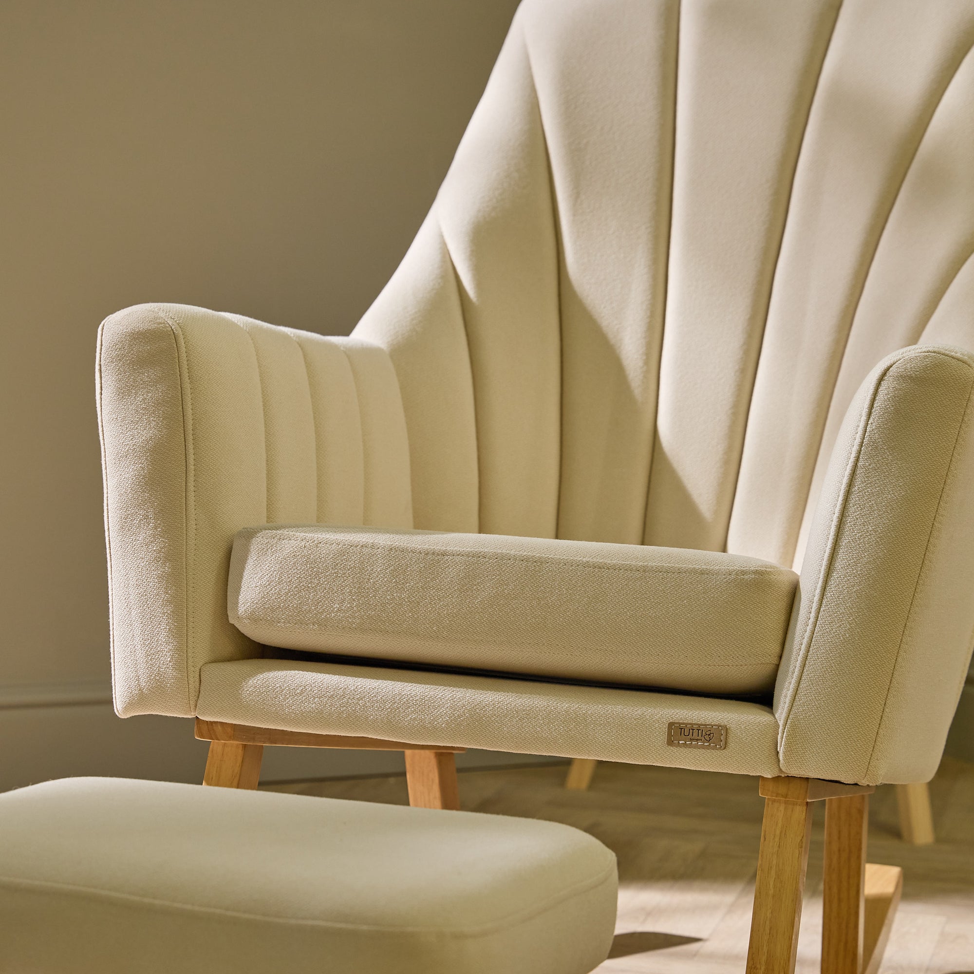 Close-up of the Danica rocking chair in cashmere, focusing on stitched fluted backrest and tactile upholstery texture in warm light