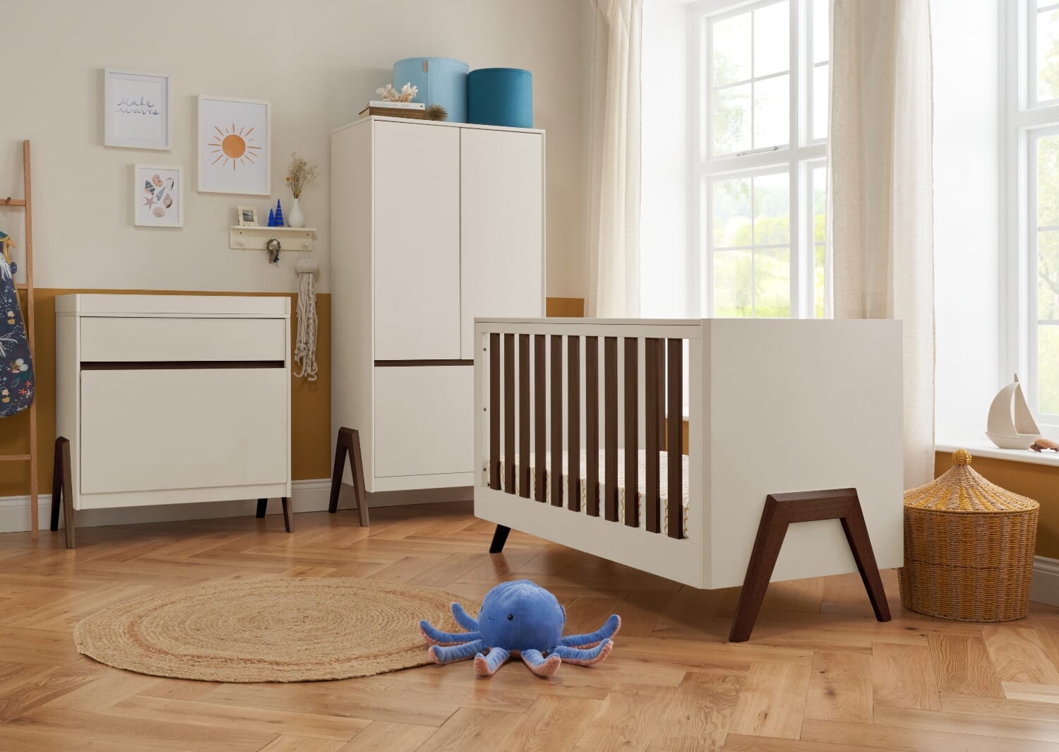 Styled nursery featuring the Fuori cot bed, wardrobe and chest changer in white sand and warm walnut, creating a warm, modern space