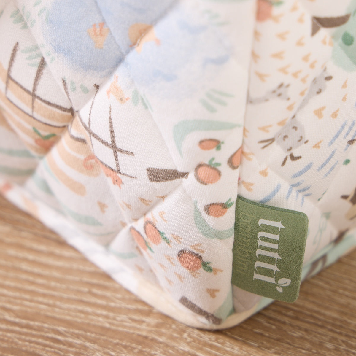 Close-up of the Good Life nappy caddy fabric, highlighting soft quilted texture, scenic print, and Tutti Bambini brand tag detail
