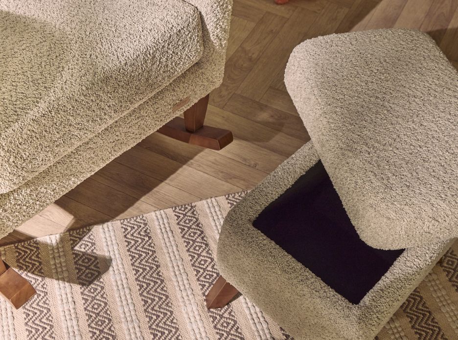 Overhead close-up of the Oscar Luxe footstool in sage boucle with open lid, revealing hidden storage and natural wood flooring.