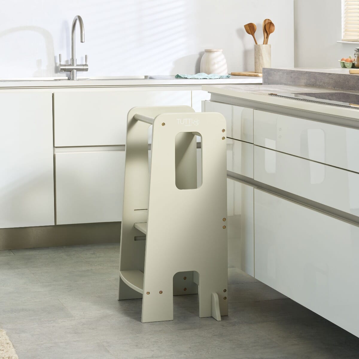 Lifestyle view of the Helping Hands Montessori toddler learning tower in mushroom finish placed by a kitchen counter, ready for toddler use