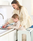 Toddler standing in the Helping Hands Montessori Learning Tower in sea mist at the sink with mum, safely engaged in washing tomatoes