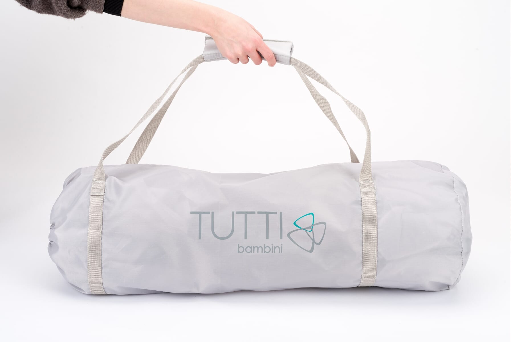 Hexa playpen in ecru packed into a compact travel bag with carry handles, highlighting its lightweight, foldable design