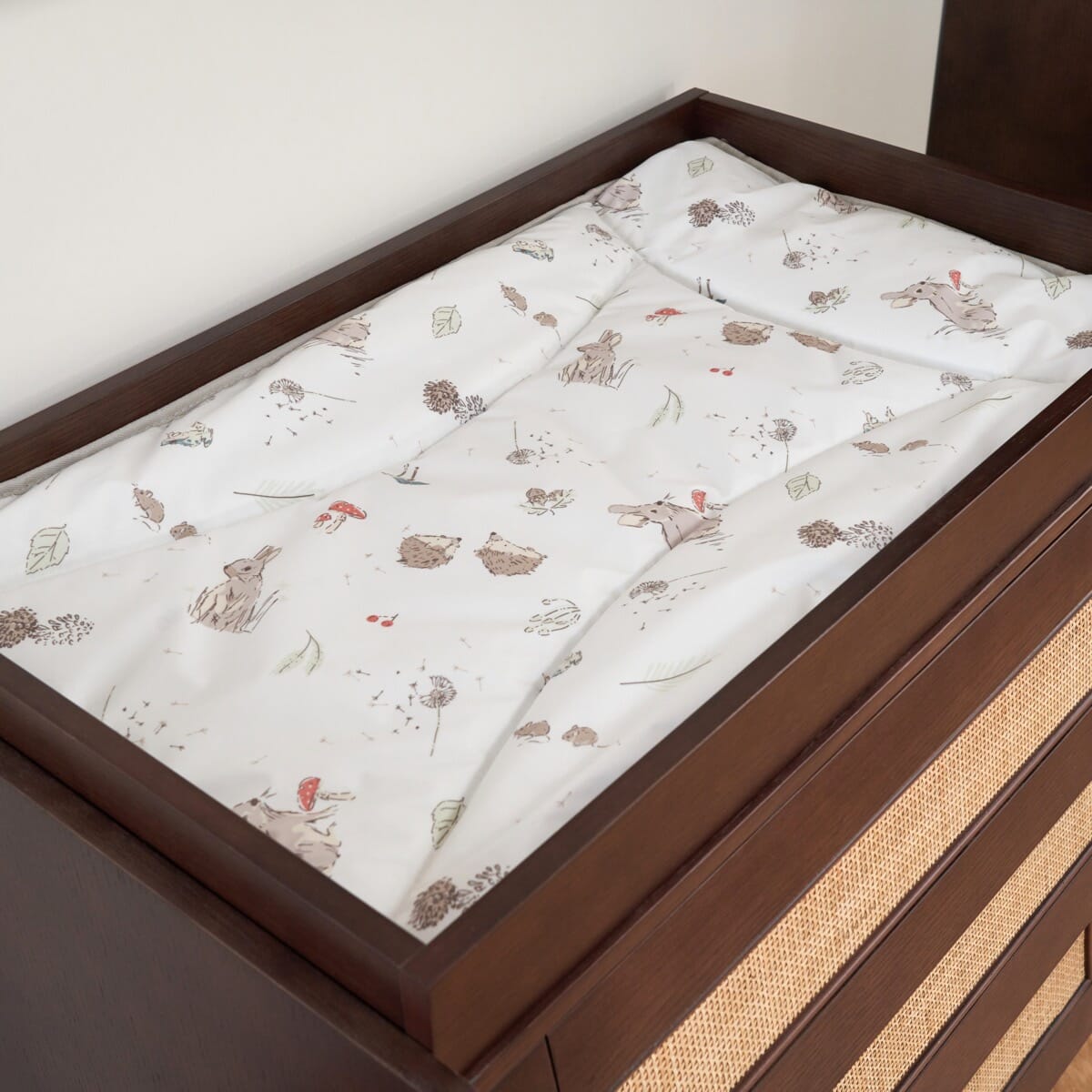 Japandi changing top in warm walnut featuring a protective frame and woodland changing mat, offering a comfortable and secure space for nappy changes.