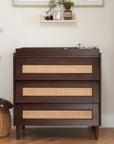 Japandi chest changer in warm walnut finish with integrated changing top and three spacious drawers, with natural textures and soft lighting for a calming, organised space.