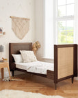 Japandi cot bed in warm walnut shown in toddler bed mode with mattress lowered and rails removed, designed to support independence and comfort for toddlers.