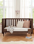 Japandi cot bed in warm walnut converted to sofa bed mode with side rails removed, offering a cosy lounging space