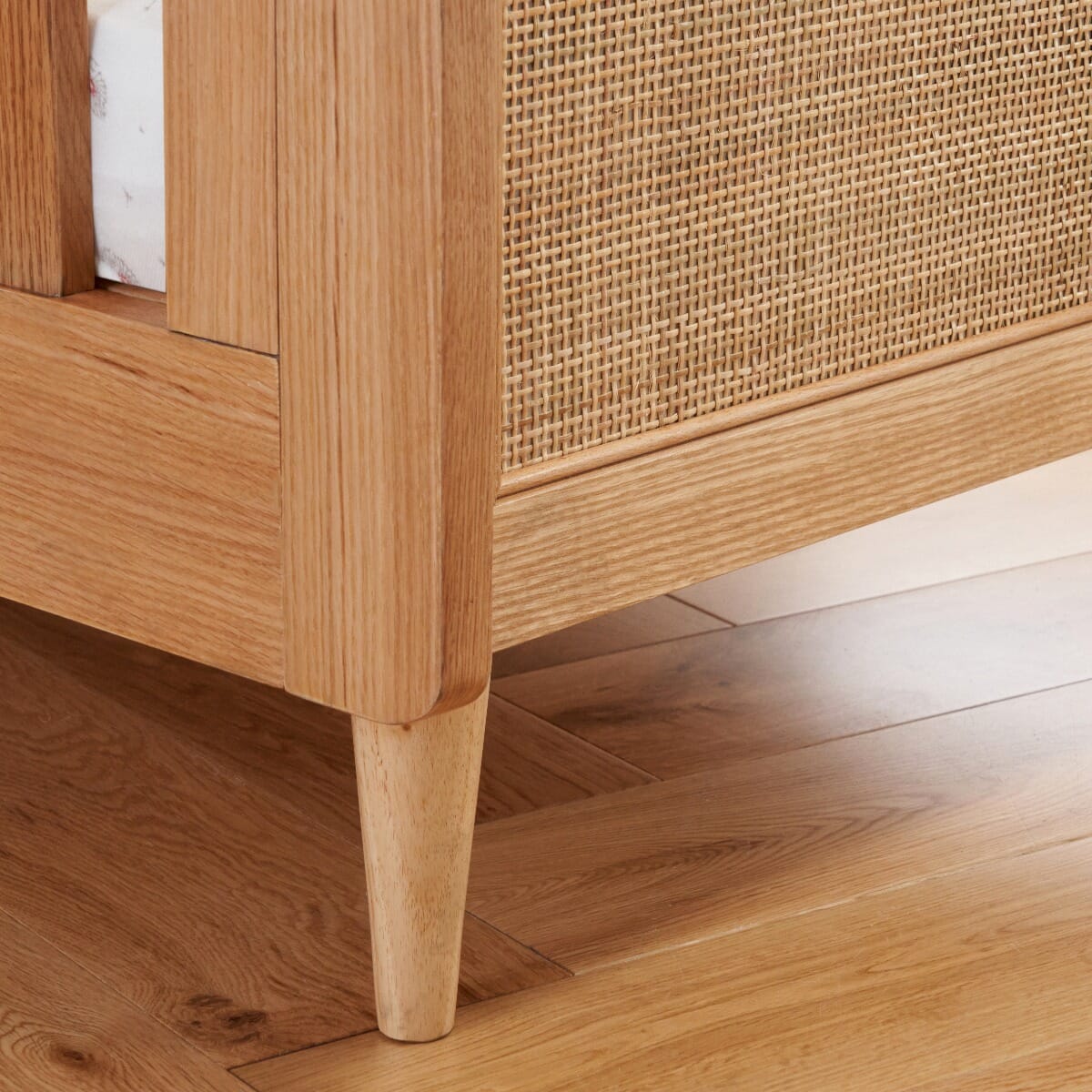 Japandi Mini Cot Bed in light oak finish showing leg detail, highlighting natural grain and tapered design for a refined look.