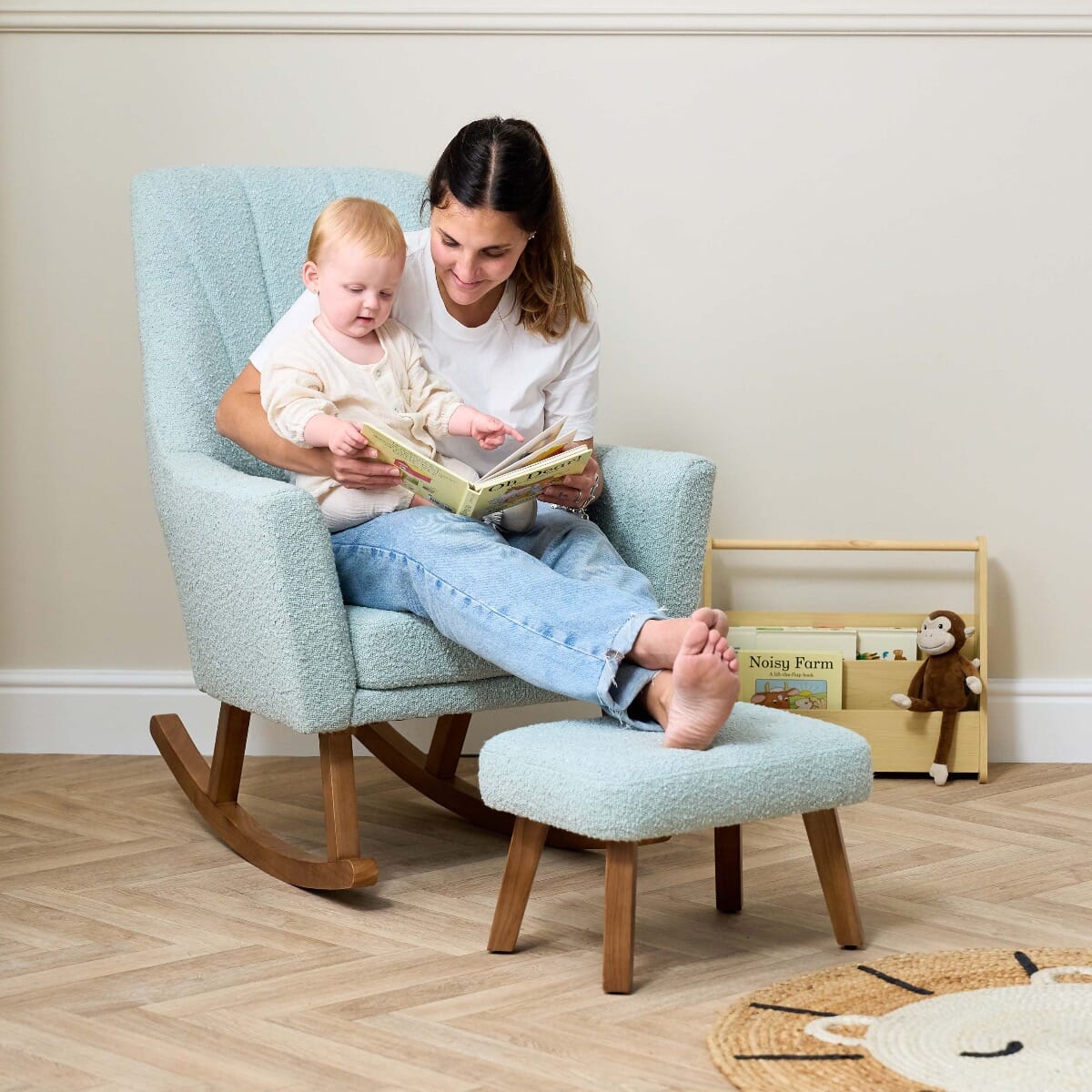 Mother reading with baby in the Jonah Luxe rocking chair and footstool in boucle ocean stone, styled for soft comfort and closeness