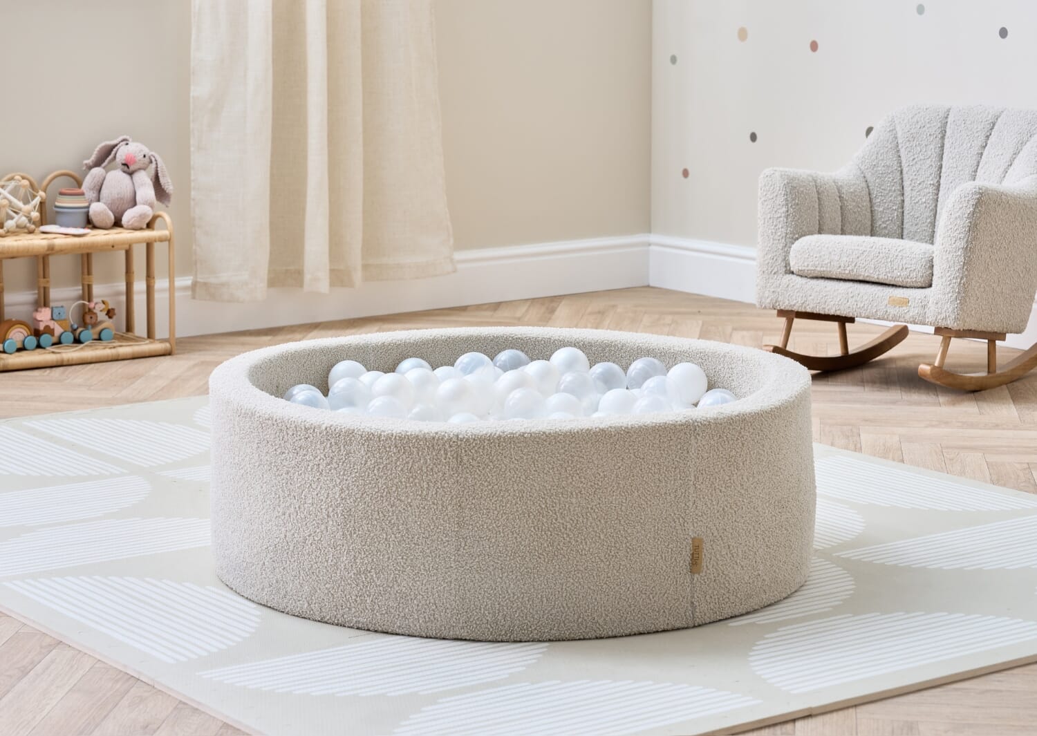 Bola baby ball pit in mushroom styled on a play mat, showing its neutral tone and rounded shape within a calm nursery setting