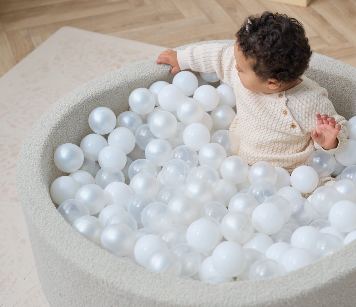 Overhead view of the Bola baby ball pit in mushroom, highlighting the cushioned rim, soft boucle texture and filled interior