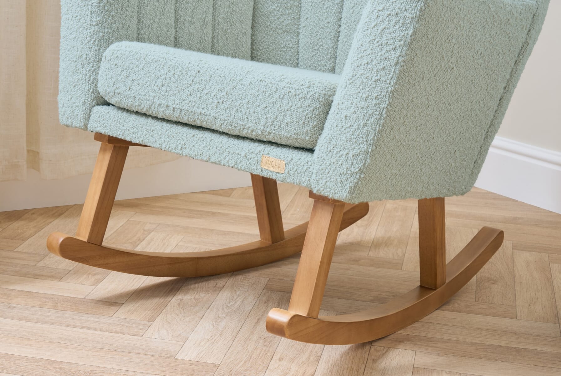 Close-up of the Jonah Luxe rocking chair in boucle ocean stone, highlighting the smooth wooden rocker base and supportive angled legs