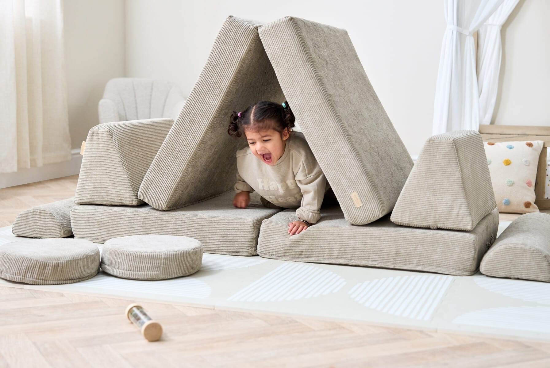 Child crawling through a den made from the Playrama kids play sofa in mushroom, demonstrating modular design for creative play builds