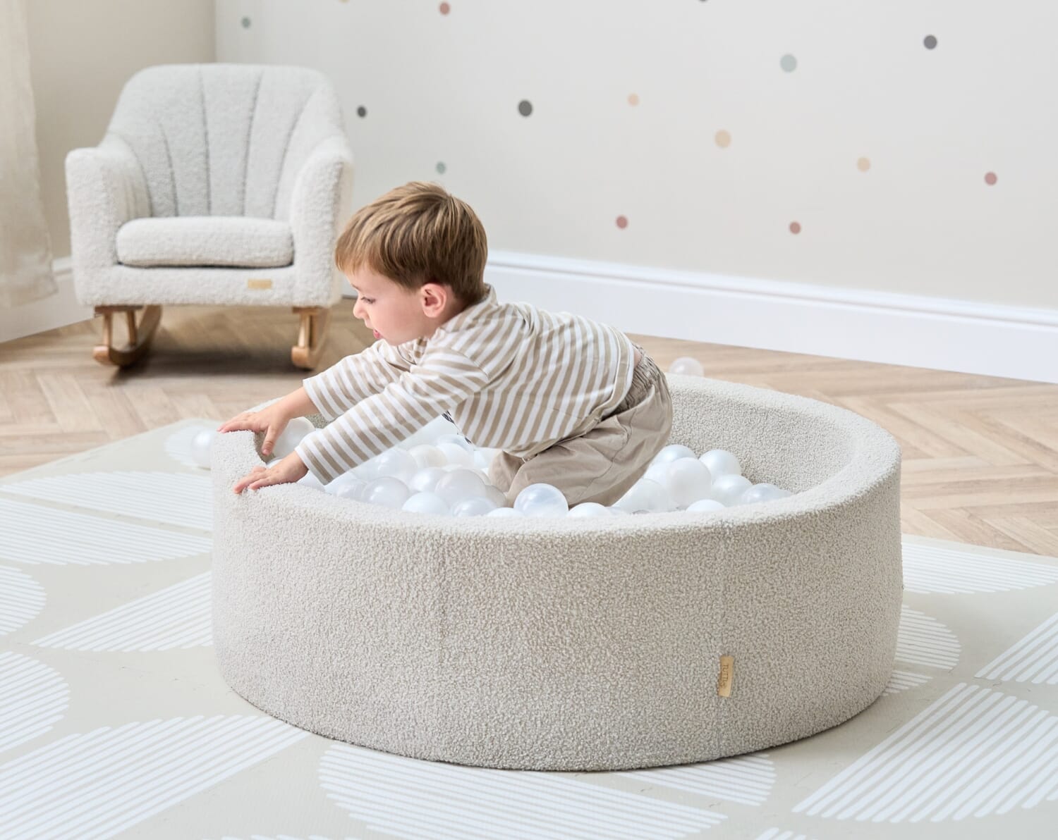 Toddler leaning into the Bola baby ball pit in mushroom, showing soft padded sides and supportive depth for safe, sensory play