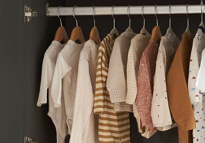 Interior view of the Rio wardrobe in slate and honey oak, showing spacious hanging rail with baby clothes neatly organised for everyday storage