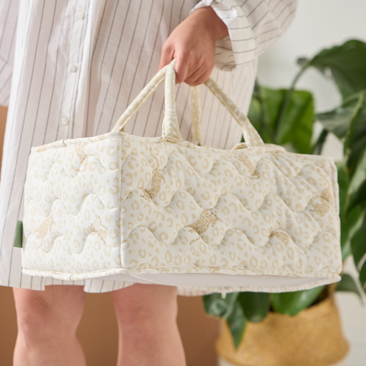 Close-up of parent carrying the Love Cats nappy caddy in beige leopard print, showing quilted finish, soft texture, and sturdy handles