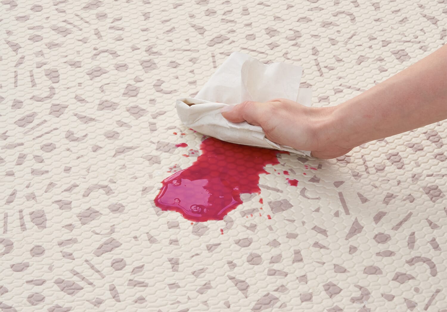 Close-up of the Bubble Terrazzo play mat showing a bright spill being wiped clean, highlighting its easy-care, wipeable surface