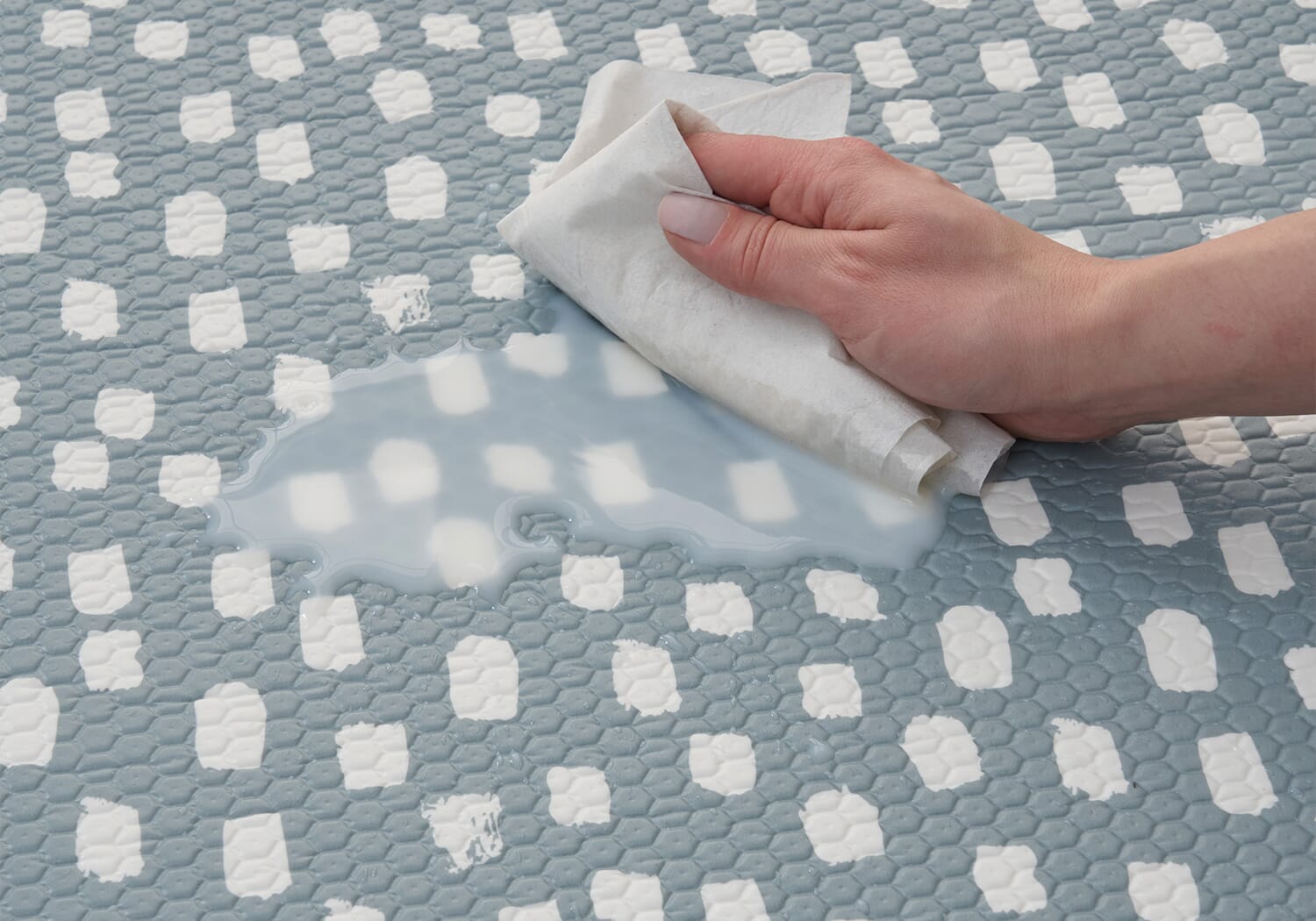 Close-up of the Cathedral Dash play mat as a spill is wiped clean, highlighting its easy-care, wipeable surface for everyday family use