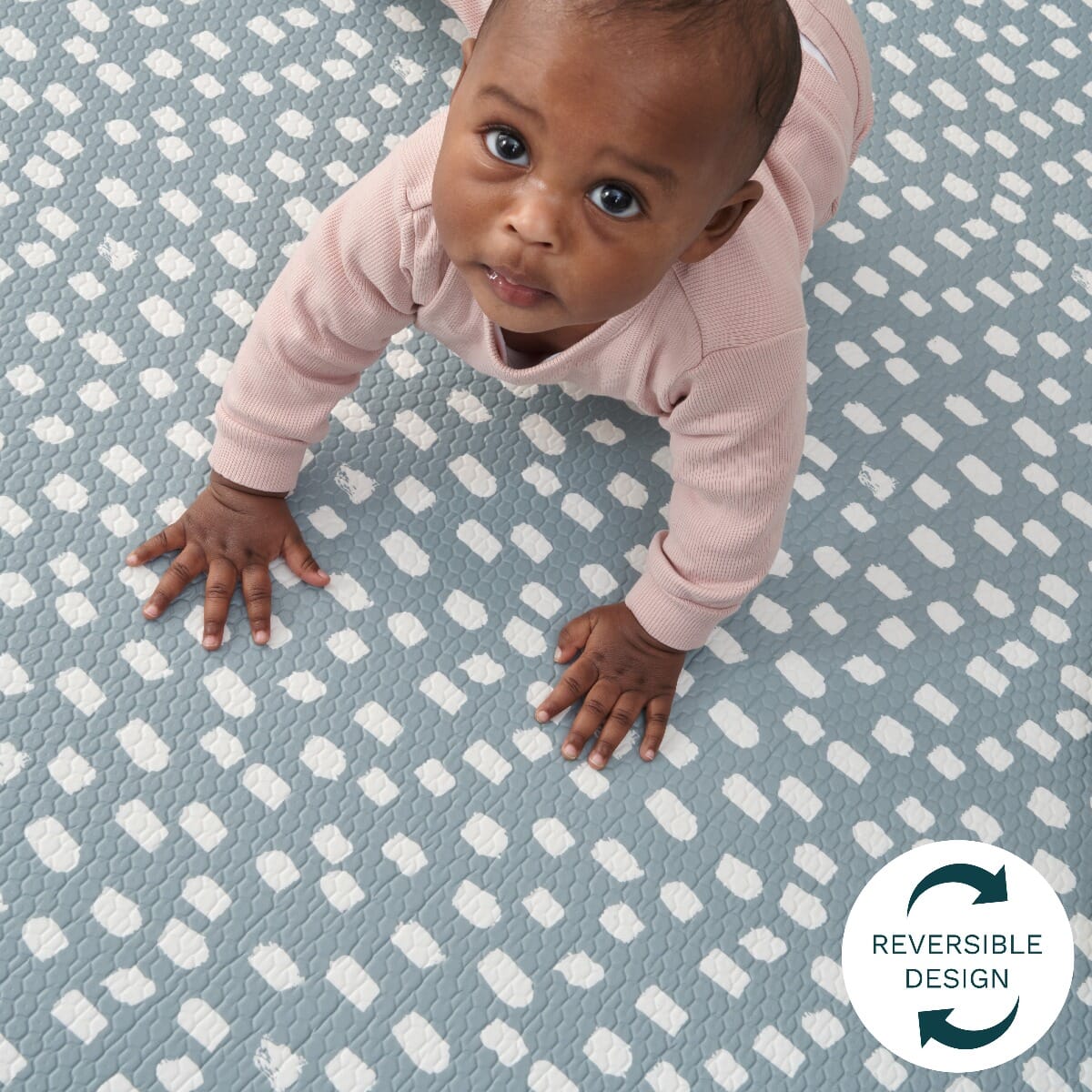 Toddler crawling on the dash side of the reversible Cathedral &amp; Dash mat, highlighting its cushioned texture and playful, calming design