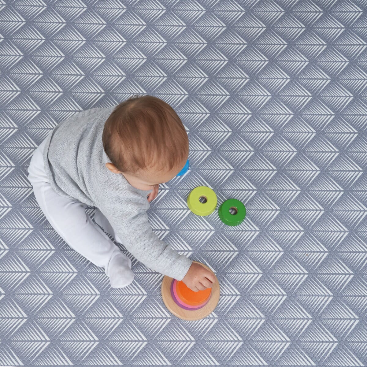 Close-up of a baby playing on the Luxury Padded XL Play Mat in fan, showing the cushioned surface and detailed geometric pattern