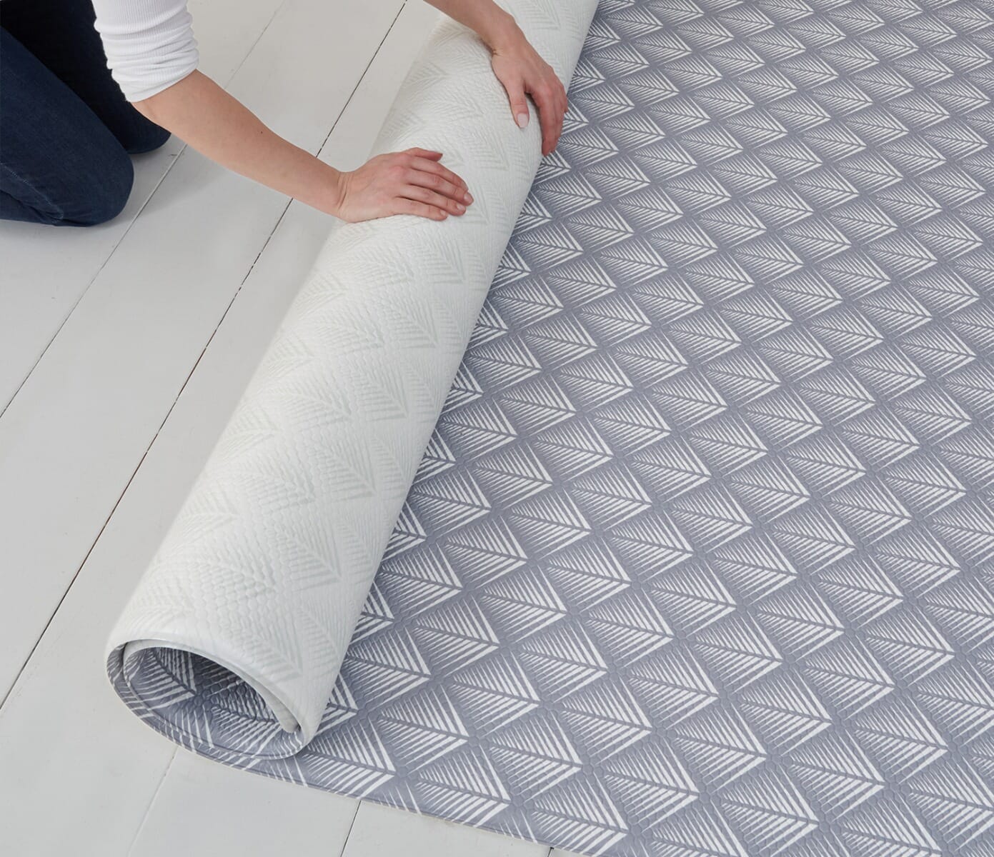 Partially rolled Luxury Padded XL Play Mat in fan design, showing reversible patterns and flexible material for simple storage and setup
