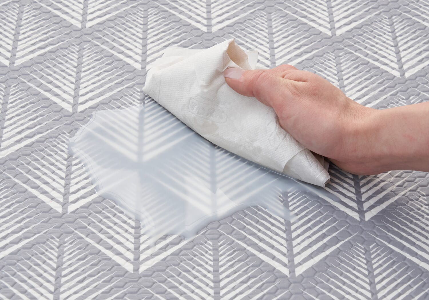 Close-up of the Luxury Padded XL Play Mat in fan design as a spill is wiped away, highlighting its easy-clean, water-resistant surface