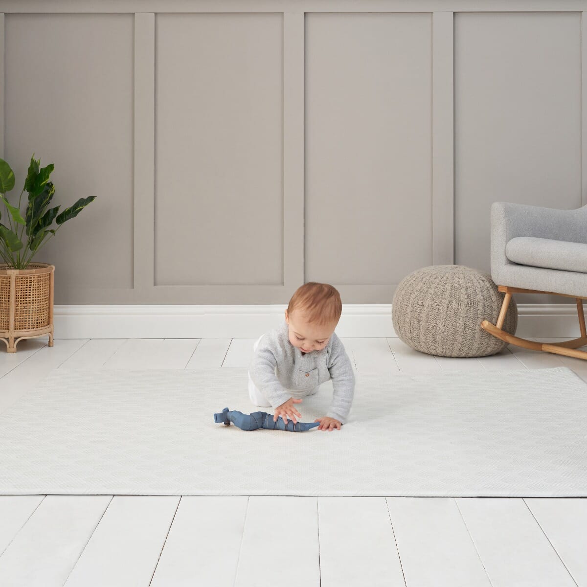 Lifestyle view of a baby playing on the Luxury Padded XL Play Mat in fan white, showcasing its soft cushioning and gentle textured design