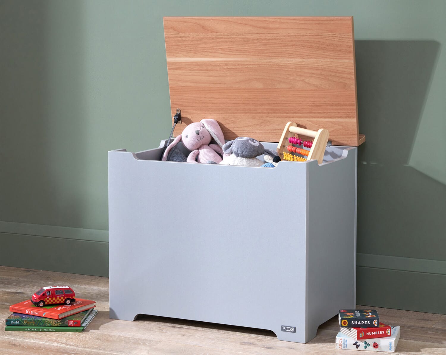 Open toy box in dove grey and oak displaying soft-close safety hinge and spacious interior filled with toys, styled in a calm playroom setting