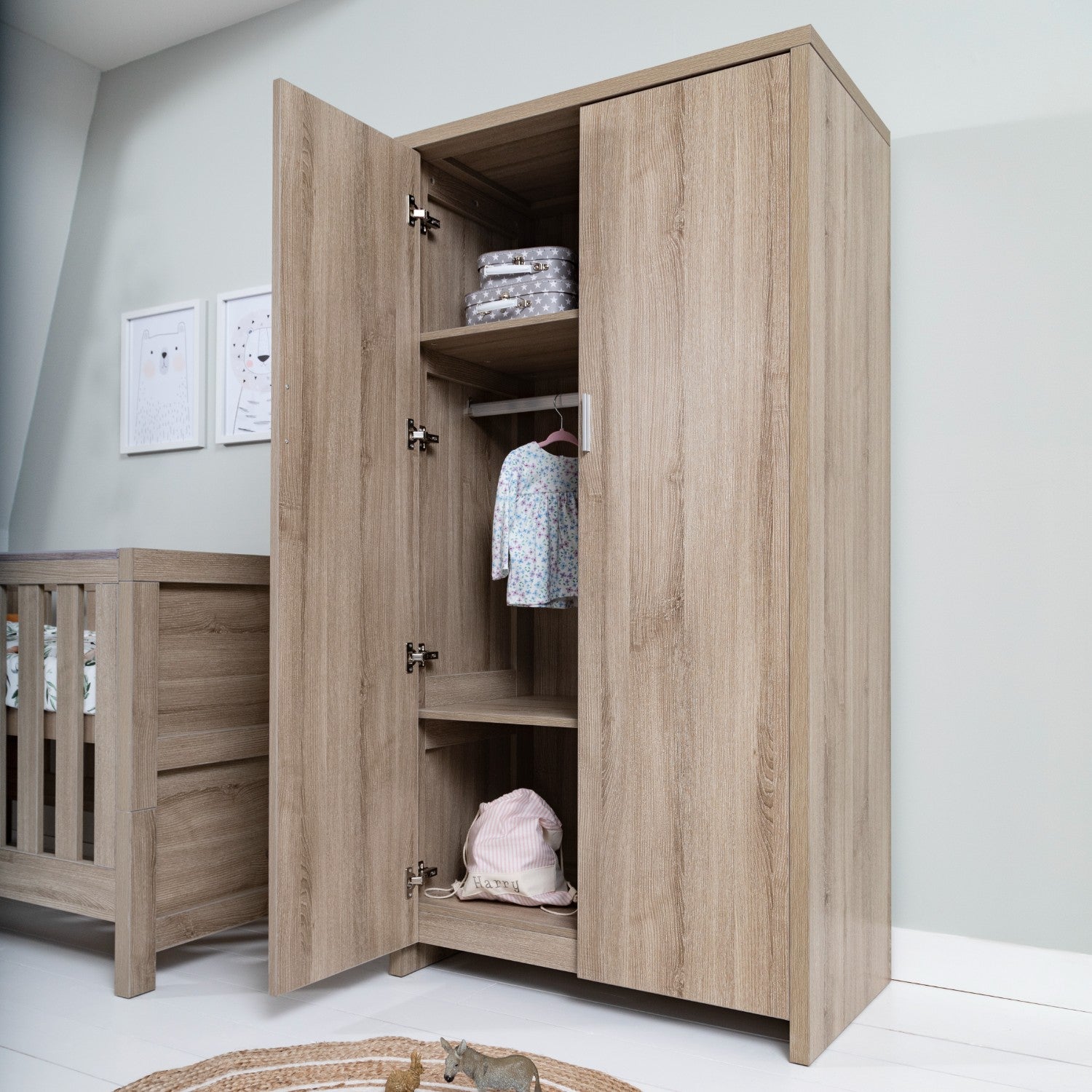 Open Modena wardrobe in oak finish showing internal hanging rail and shelving for organised baby clothing storage.