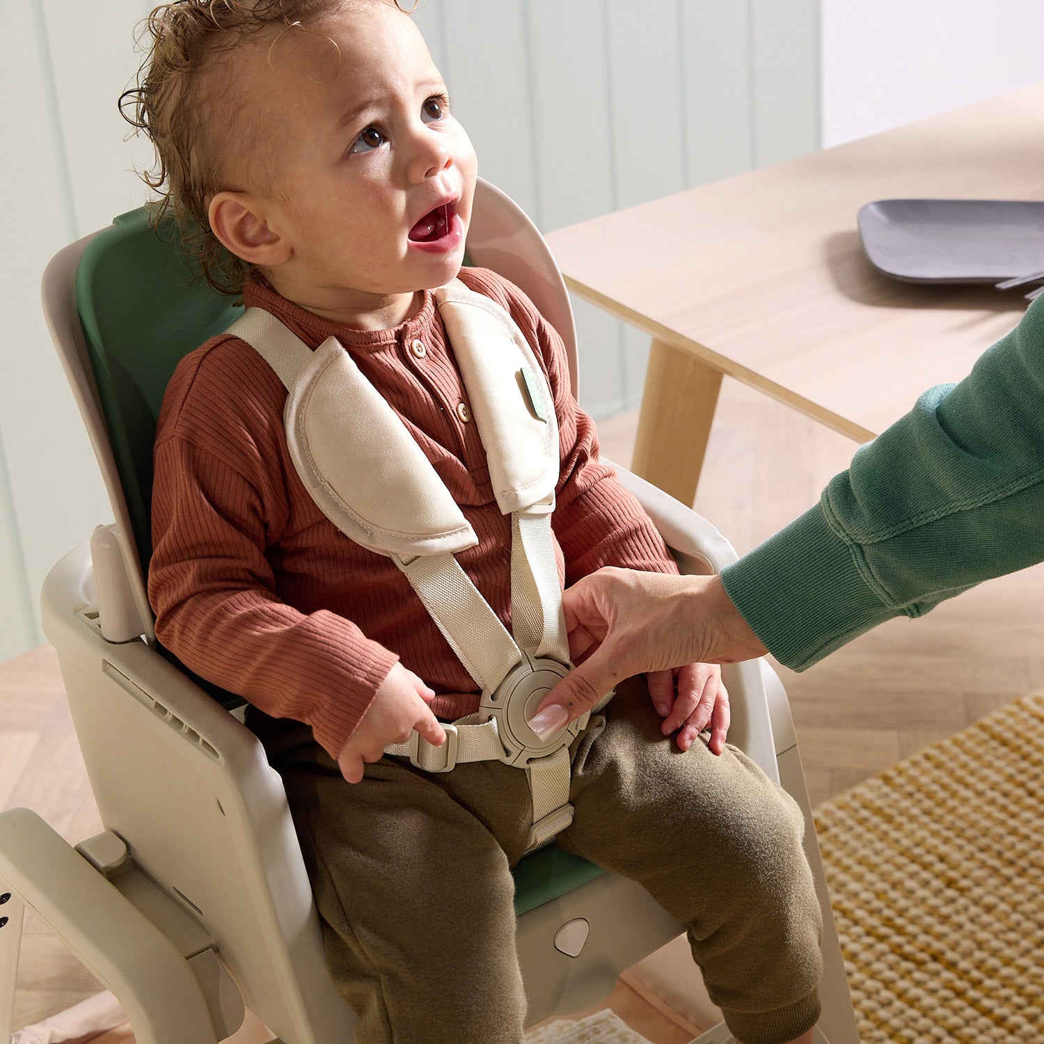 Child seated in the nova maison 7 in highchair in parnsip, secured with padded harness and supported upright for mealtimes.