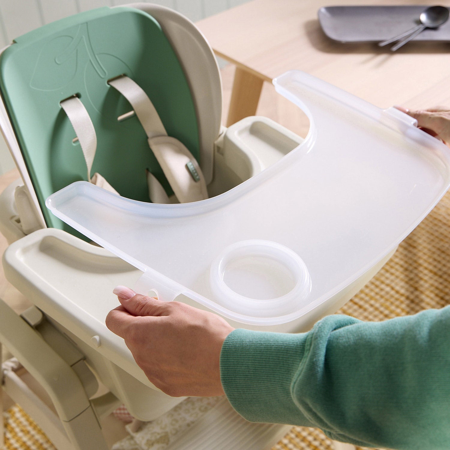Lifestyle image of the nova maison 7 in highchair in parnsip positioned at a dining table in a calm, modern kitchen setting.