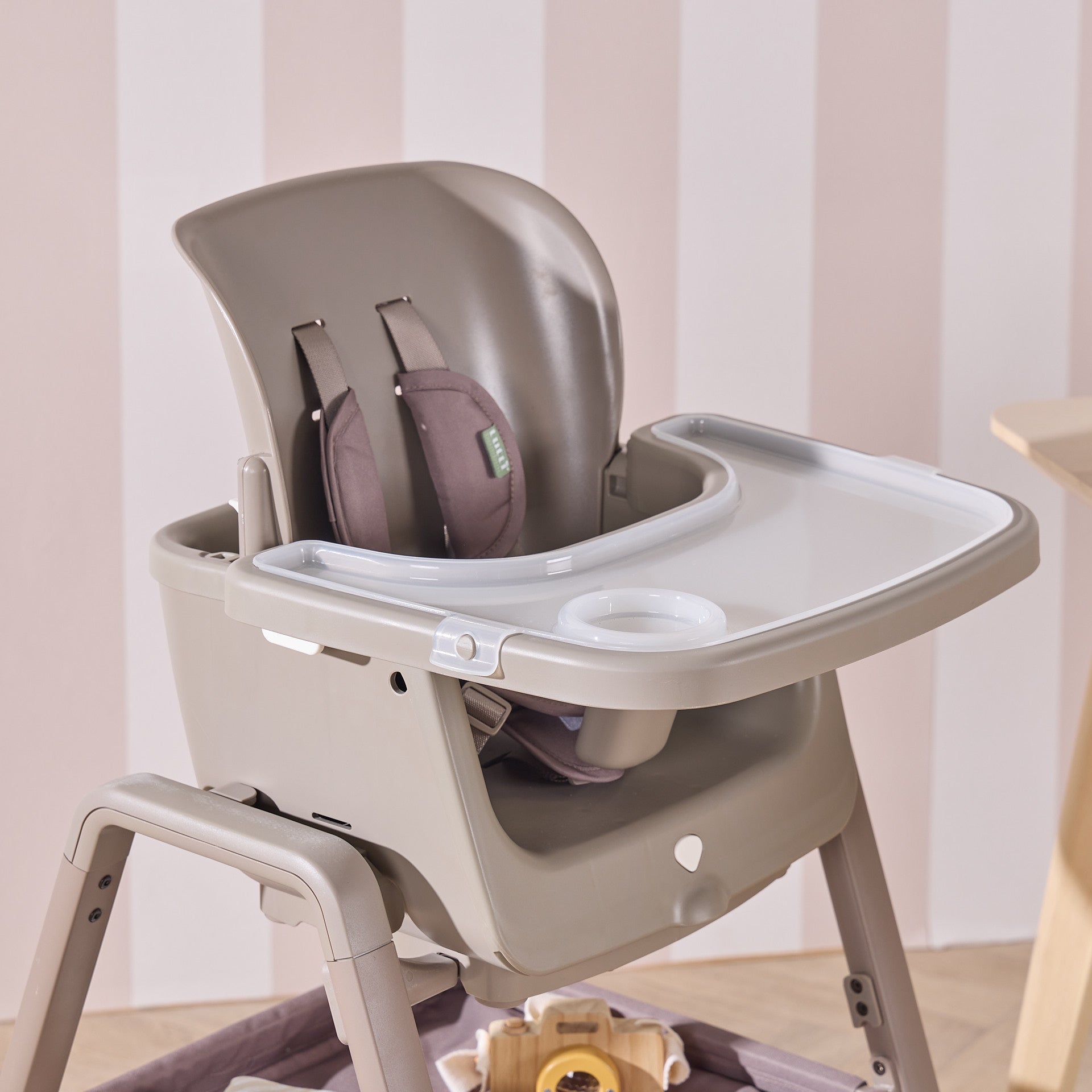 Angled view of Nova Maison highchair in truffle featuring wide tray, padded harness and sturdy adjustable frame.