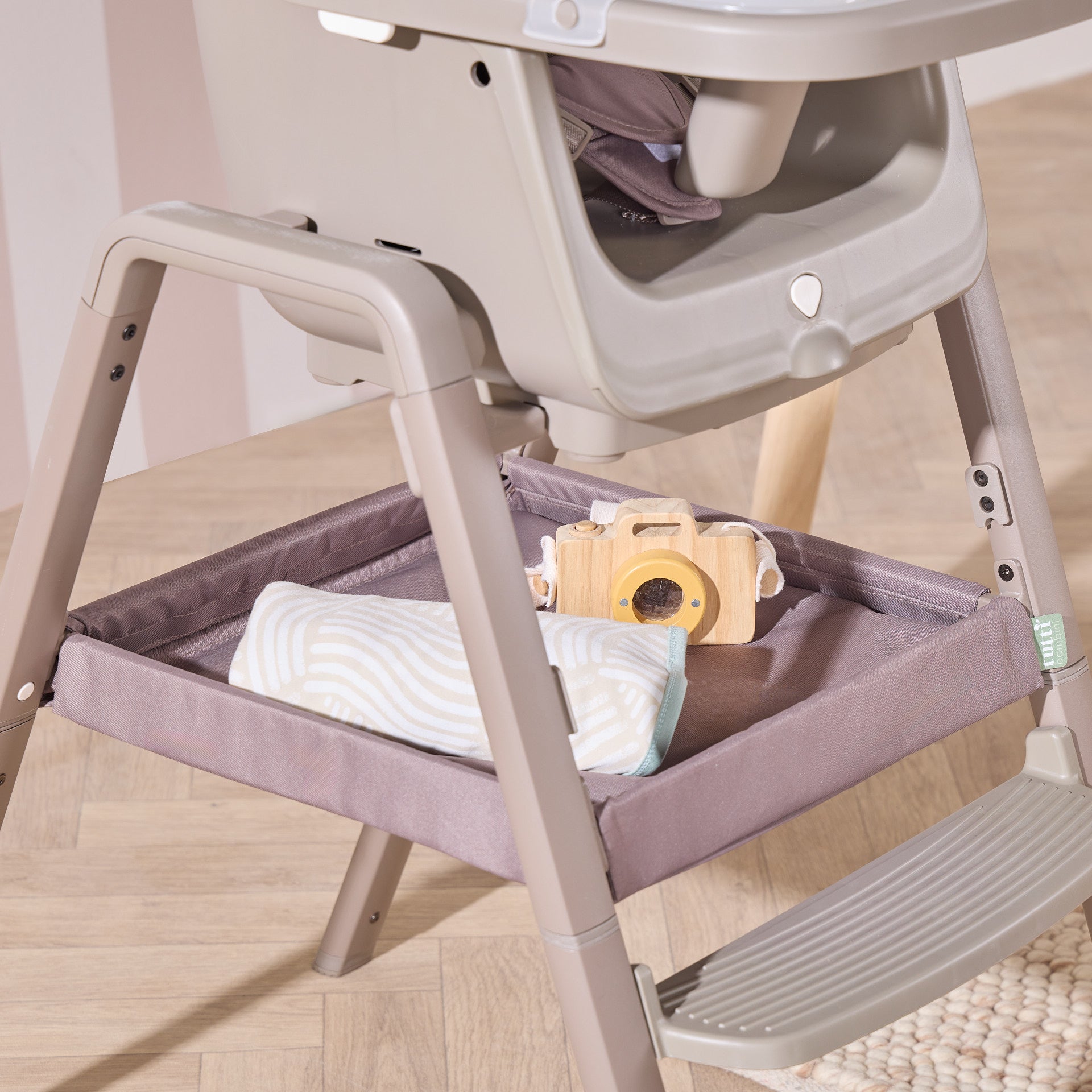 Nova Maison highchair in truffle with under-seat fabric storage tray holding baby essentials for easy access.