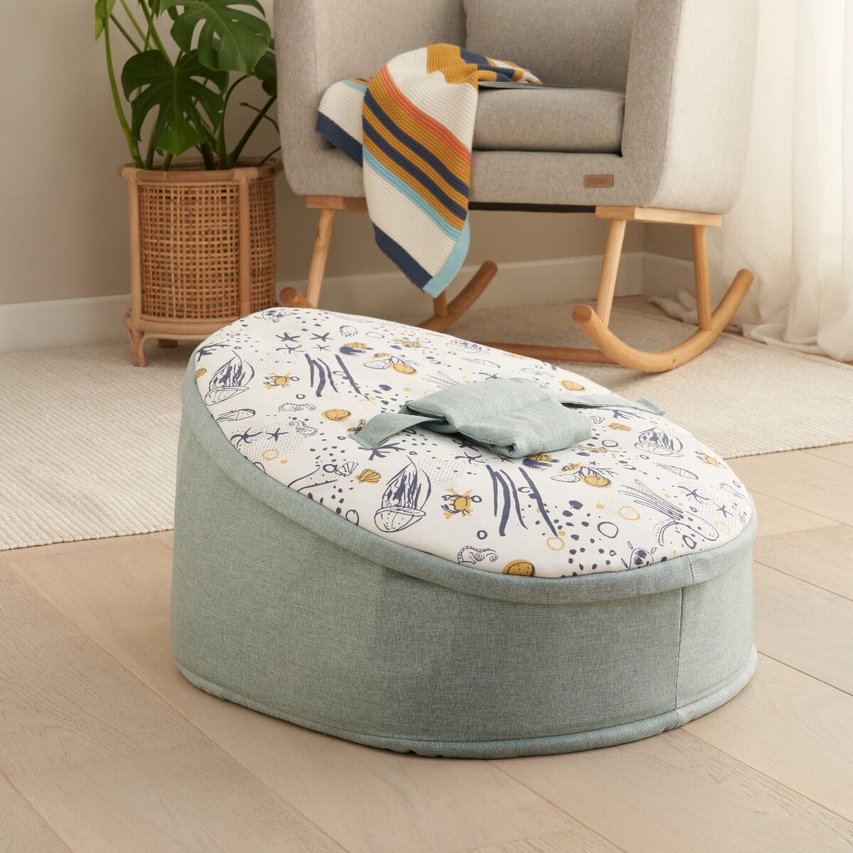 Lifestyle view of the Our Planet baby beanbag showing the integrated safety strap and buckle, designed to support baby comfortably in everyday use