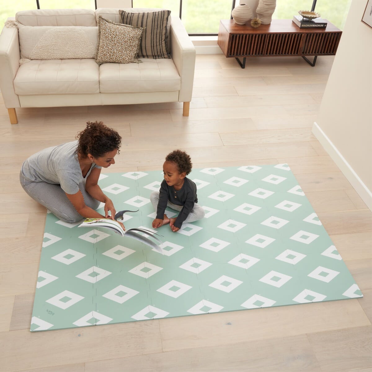 Parent and toddler reading together on the diamond mint puzzle playmat, highlighting its spacious cushioned surface for comfortable playtime
