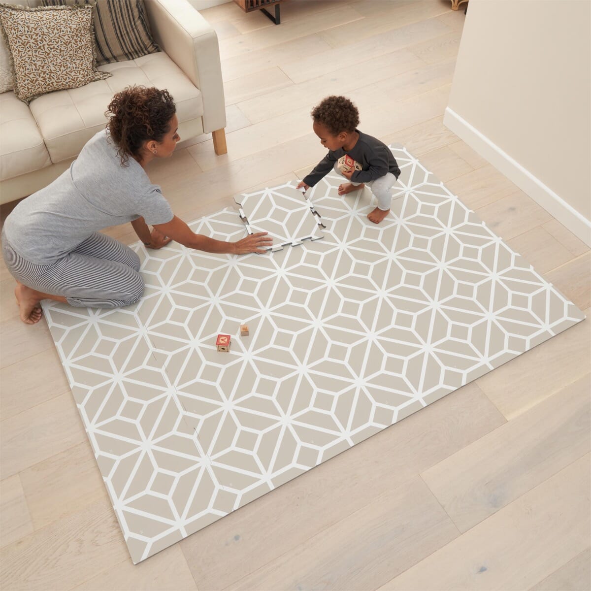 Lifestyle scene showing parent and child playing on the tiles white sand puzzle playmat, offering cushioned comfort for floor play