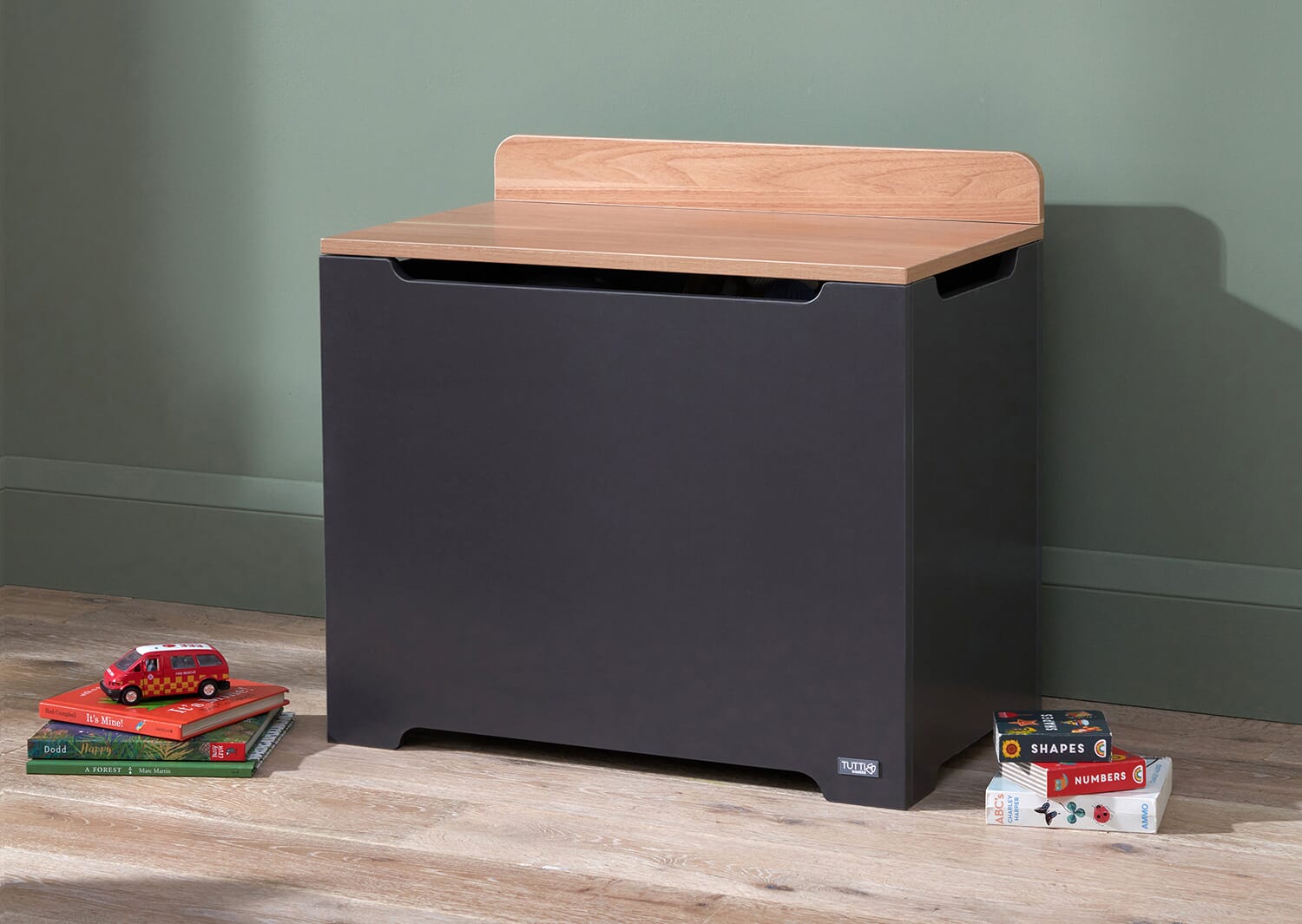 Lifestyle view of the Rio toy box in slate grey and honey oak, styled with children’s books nearby and a clean, modern nursery backdrop