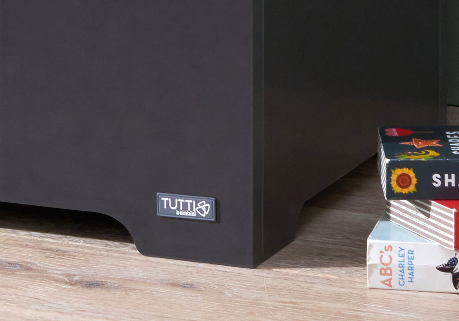 Close-up of the Rio toy box in slate grey and honey oak, highlighting the Tutti Bambini logo and smooth painted finish at the base