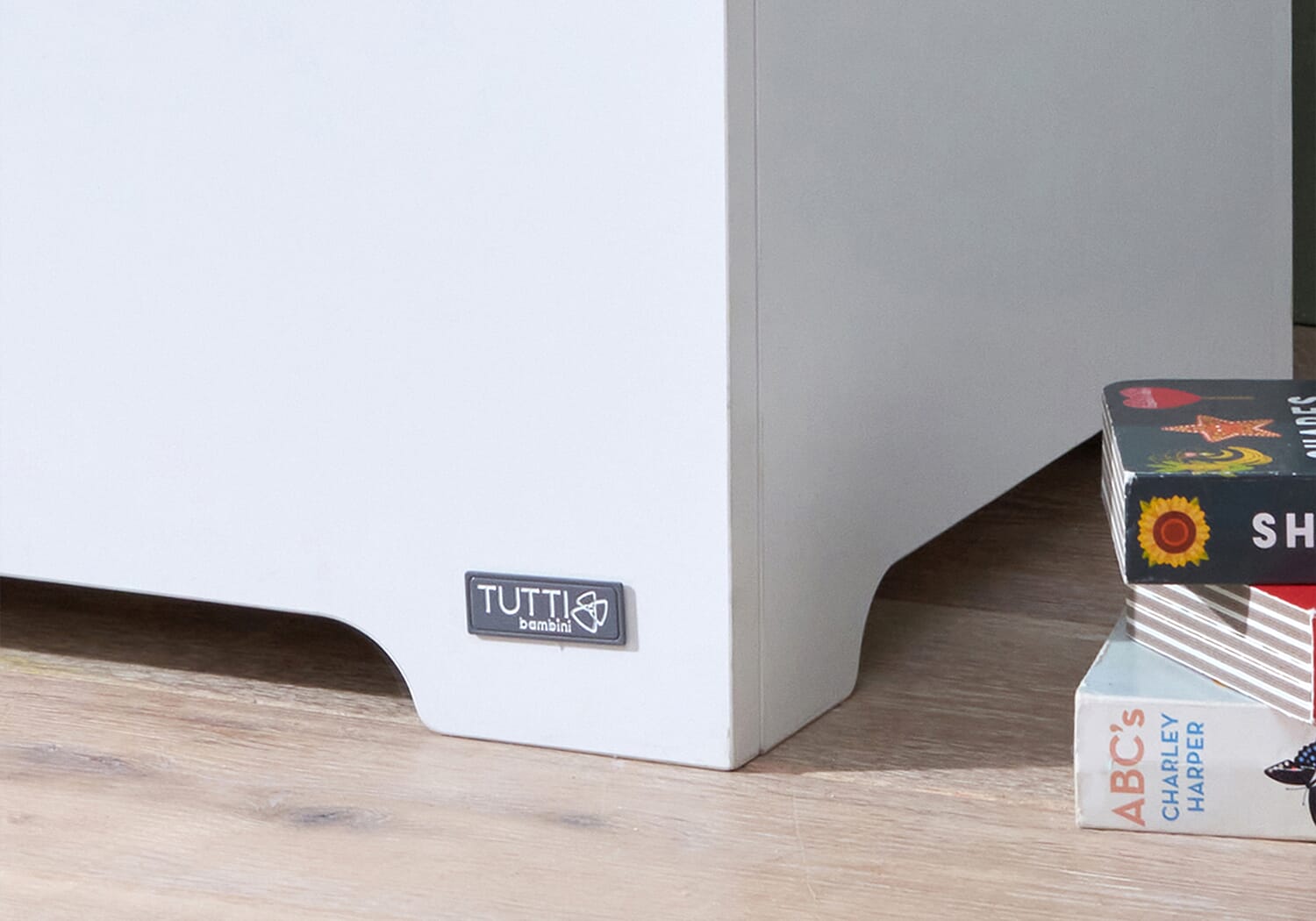 Close-up of the Rio toy box base in white and dove grey, showing the Tutti Bambini logo and smooth curved detailing at the bottom edge