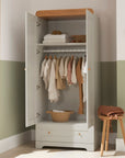 Front view of the Rio wardrobe in Honey Oak and Dove Grey with doors open, showing internal hanging rail, shelf, and bottom drawer for versatile nursery storage.