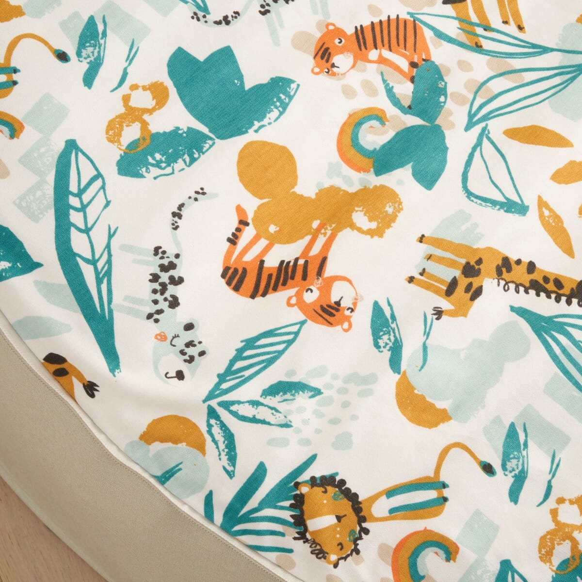 Fabric close-up of the Run Wild baby beanbag seat, showcasing colourful animal illustrations and soft, baby-friendly textile