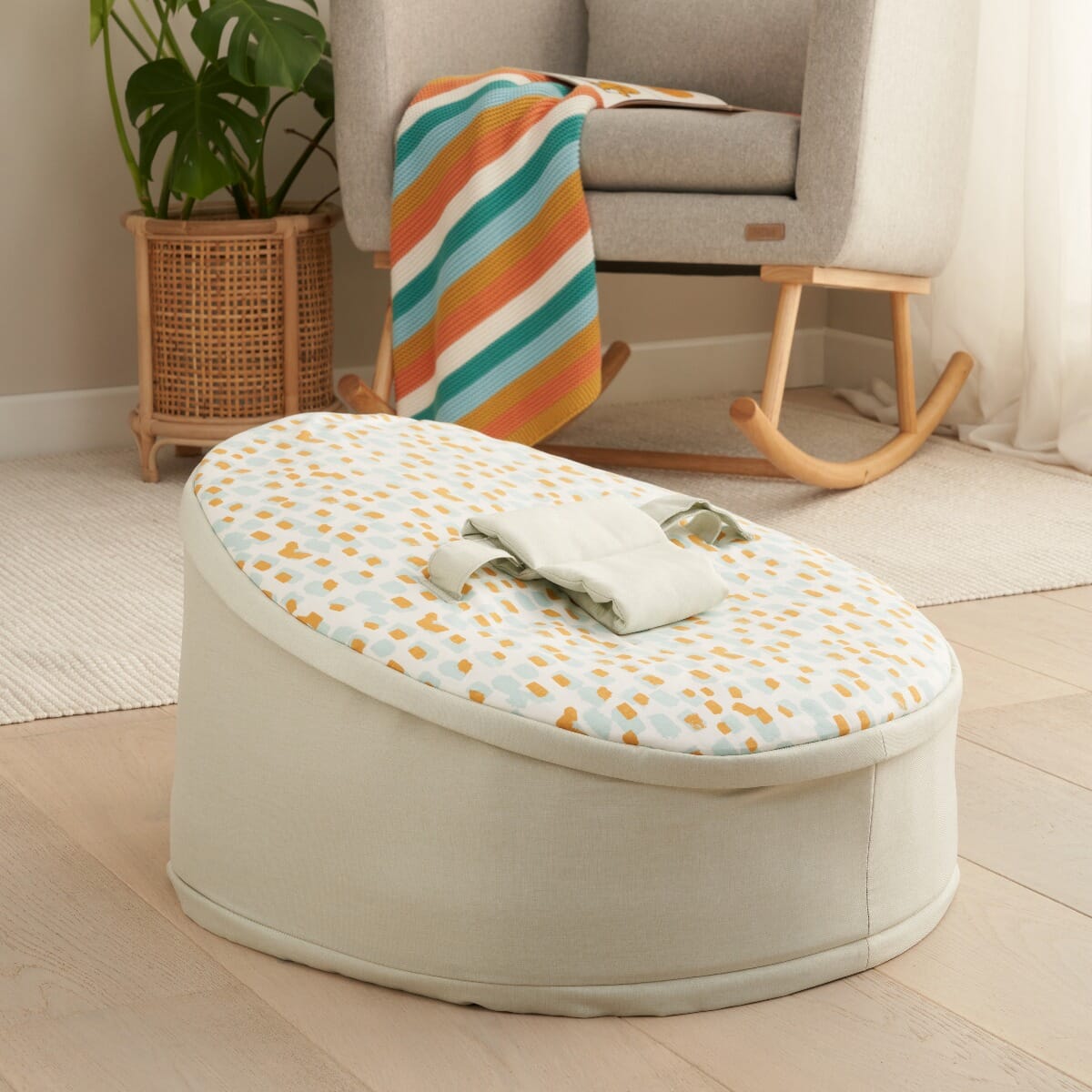 Lifestyle view of the Run Wild baby beanbag showing padded safety strap in use, styled in a calm nursery with a rocking chair backdrop